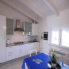 Cucina moderna bianca con tavolo blu e finestra.