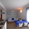 Salotto con cucina blu e tavolo, divano e decorazioni marina.
