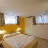 Letto matrimoniale con parete gialla e finestre.
