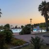 Piscina al tramonto circondata da palme e vista mare.