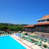 Piscina affiancata da edificio con tetti rossi.