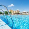 Bordo piscina con ombrelloni e edifici sullo sfondo.