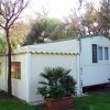 Casa mobile bianca con veranda tra alberi.
