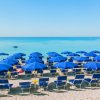 Spiaggia con ombrelloni e sedie blu.