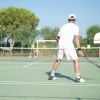 Un uomo gioca a tennis su un campo all'aperto.