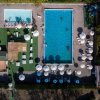 Vista aerea di due piscine con lettini e ombrelloni su un prato verde.