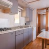 Cucina moderna con piano cottura, lavello, armadietti grigi e tavolo.