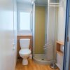 Bagno con doccia angolare, parquet chiaro e sanitari bianchi. Finestra luminosa.