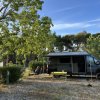 Un camper parcheggiato in una radura, con persone sedute all'esterno.