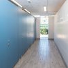 Corridoio con cabina blu e porta aperta sullo sfondo.