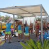 Lezione di fitness all'aperto sotto una tettoia con partecipanti in cerchio.