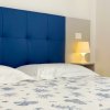 Un letto con testiera blu, lampada accesa e copriletto con disegni blu.
