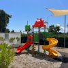 Parco giochi con scivoli colorati e una copertura in tela nel cielo azzurro.