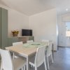 Sala da pranzo con tavolo, TV e porta sul balcone.