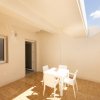Terrazza esterna con tavolo e sedie bianche.