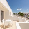 Terrazza bianca con tavolo e sedie, cielo blu limpido.
