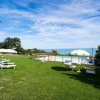 Piscina su prato verde con ombrelloni e vista mare.
