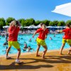 Tre istruttori fronte piscina animano il pubblico.