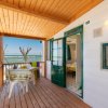 Una veranda con tavolo e sedie, affacciata sul mare, con porta verde aperta.