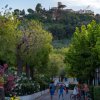 Strada del campeggio con persone e biciclette, vista di un paese su una collina sullo sfondo.