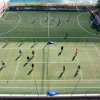 Campo sportivo con giocatori di calcio e pallavolo visti dall'alto.