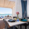 Sala da pranzo con vista mare, tavolo apparecchiato, fiori rosa, tenda blu.