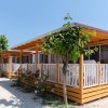 File di bungalow in legno con verande coperte, circondate da alberi e arbusti.