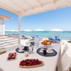 Tavolo apparecchiato sotto una veranda, vista sulla spiaggia e sul mare.