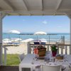 Tavolo all'aperto con vista mare e ombrelloni bianchi in spiaggia.