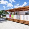 Casa mobile esterna con terrazza in legno e sedie bianche.