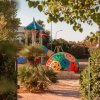 Parco giochi colorato tra alberi e piante.