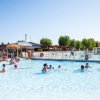 Persone in piscina con sole e ombrelloni.