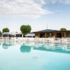 Piscina vuota riflette cielo e ombrelloni.