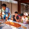 Persona serve pizza a bambini seduti.