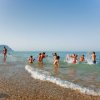 Bambini giocano in acqua lungo la riva.