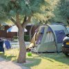 Tenda con tavoli e sedie vicino a un'auto in campeggio.
