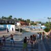 Gruppo di persone segue una lezione di danza all'aperto vicino a una piscina.