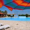 Piscina all'aperto con lettini e ombrelloni colorati su terrazza in pietra.