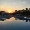 Piscina all'aperto al tramonto con palme e sedie a sdraio sullo sfondo.