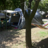 Campeggio con tenda, sedie, tavolo e amaca colorata tra gli alberi.