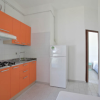 Cucina con mobili arancioni, fornelli a gas e frigorifero bianco.