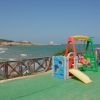 Area giochi colorata con vista mare, accanto a una staccionata in legno.