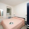 Una camera da letto con letto matrimoniale e copriletto rosa, una finestra aperta e un armadio blu.