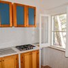Cucina con mobili in legno e vetro blu, lavello e fornelli, finestra aperta.