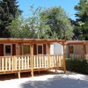 Bungalow in legno tra gli alberi, con veranda e porte-finestre.