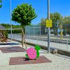 Area giochi con altalene e scivolo, circondata da alberi e recinzioni.