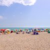 Spiaggia con ciottoli, ombrelloni colorati e mare calmo.