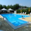 Piscina all'aperto con sedie a sdraio bianche, ombrelloni gialli e vegetazione circostante.