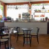 Interno di un bar con tavoli, sedie e scaffali di bevande e snack.