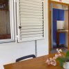 Tavolo di legno con pianta, finestra con persiane e porta aperta verso cucina.